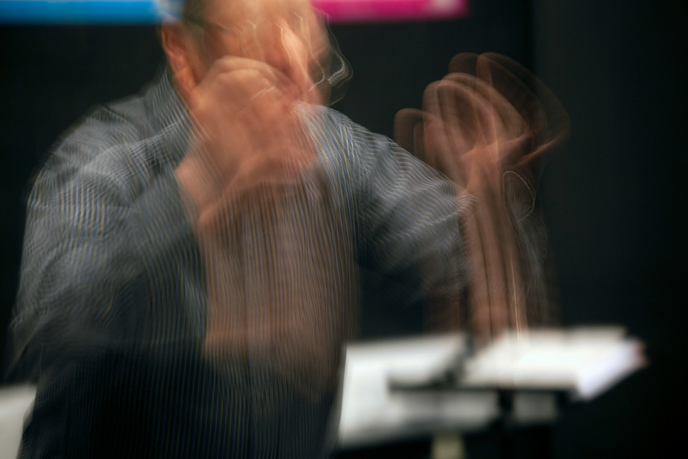 A conductor leading an orchestra to achieve shared rhythm and flow