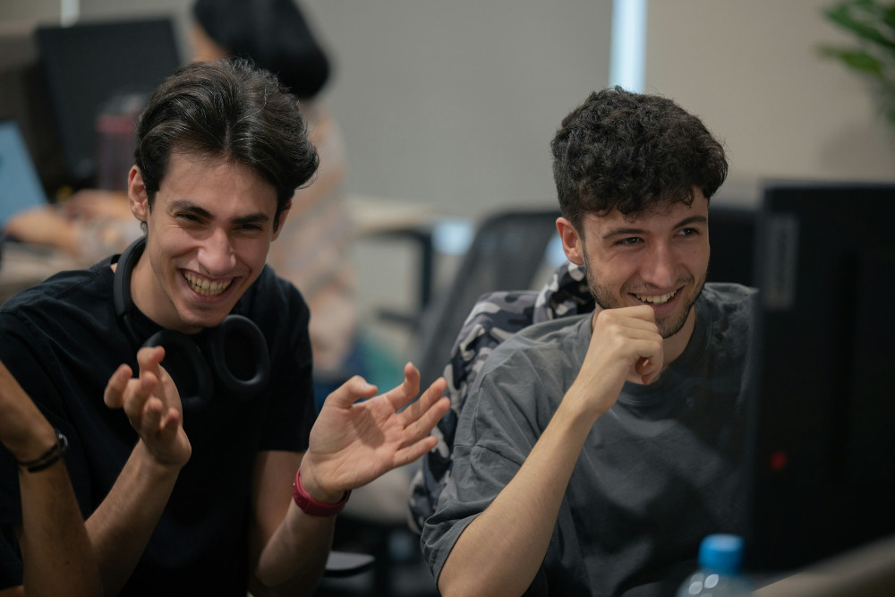 Colleagues smiling while chatting in front of computer screens