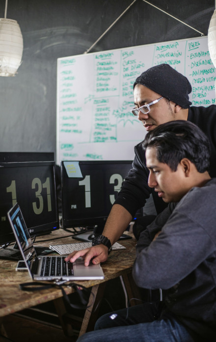 Two man discuss work in front of a laptop