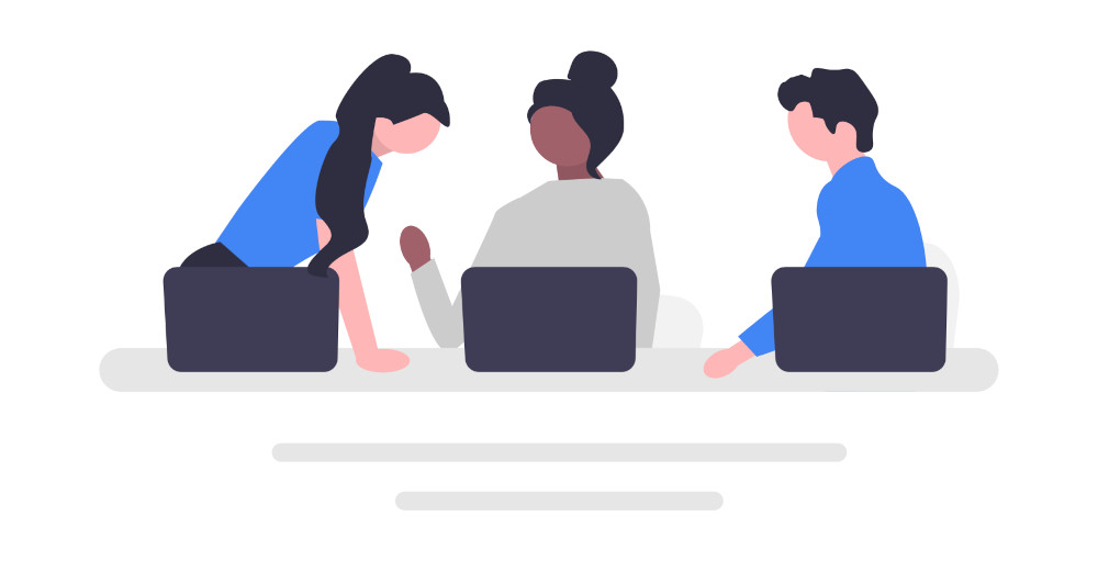 Team in discussion at a table with laptops