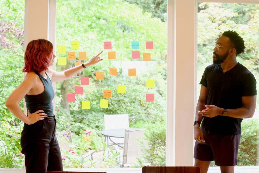 Colleagues discuss work while handling physical sticky Kanban notes